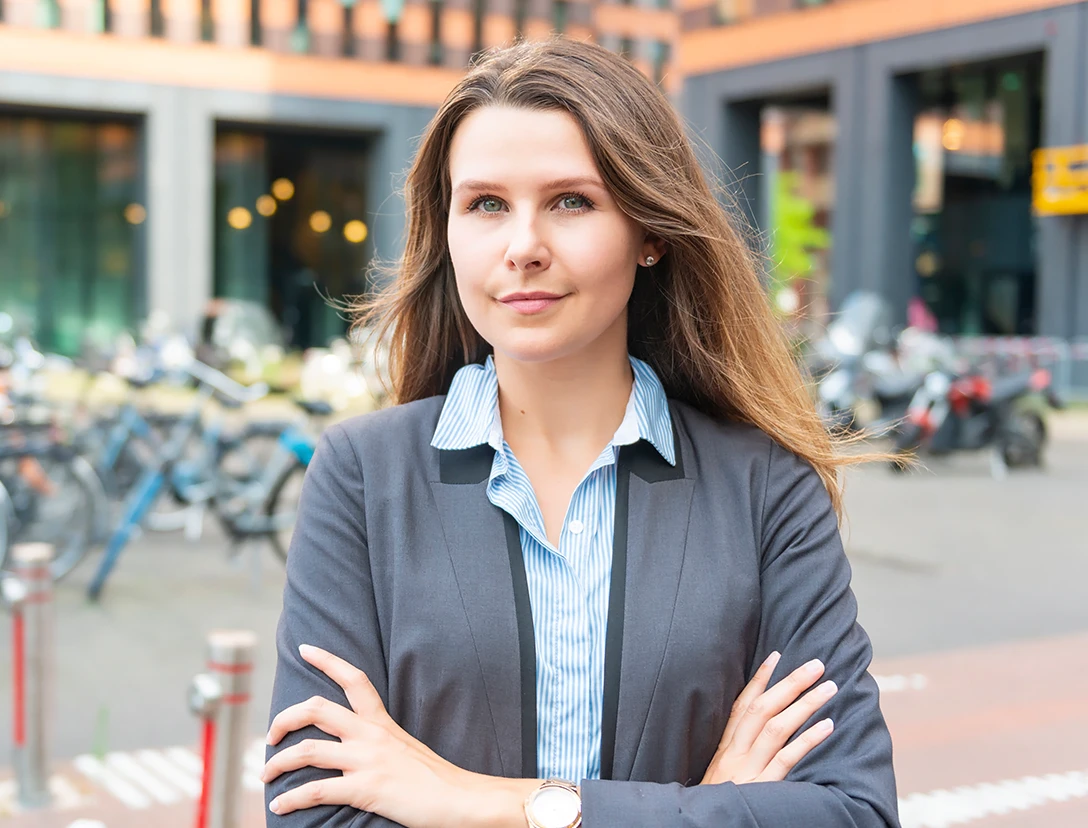 Junge Frau im Business-Outfit vor Fahrrädern betont, dass Wirtschaftsprüfer für stabile und sichere Arbeitsplätze sorgen.